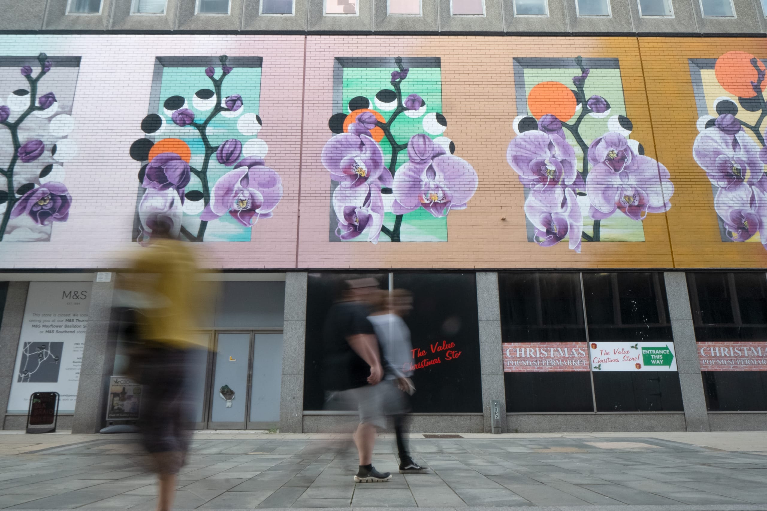 Photograph of the front end of street art, pedestrians in the foreground have motion blur effects on them.